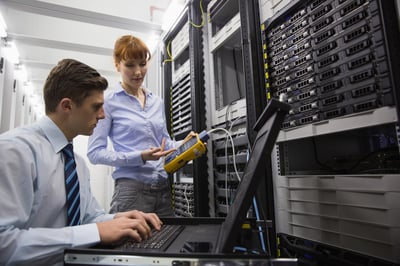 Team of technicians using digital cable analyser on servers in large data center